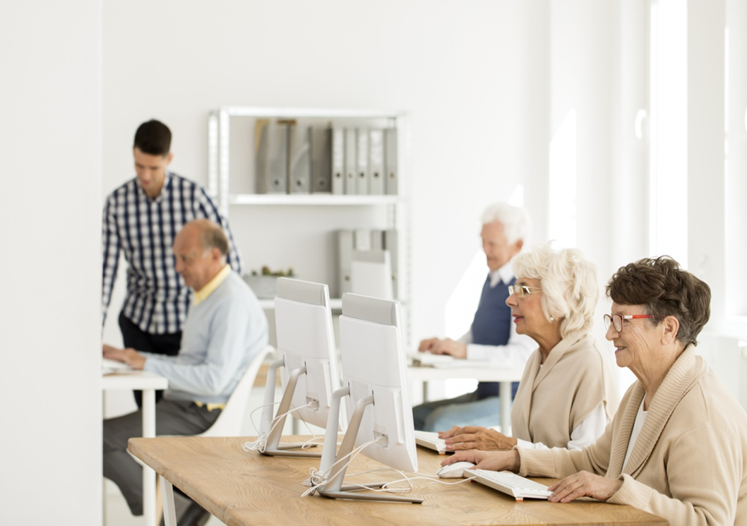 Young adult teaching seniors to use computers