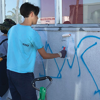 teenager painting over grafitti